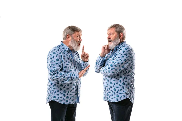 Hombre mayor discutiendo consigo mismo en el fondo del estudio blanco . — Foto de Stock