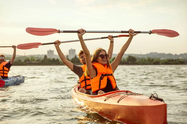 Arka planda gün batımı ile nehir üzerinde kano mutlu arkadaşlar
