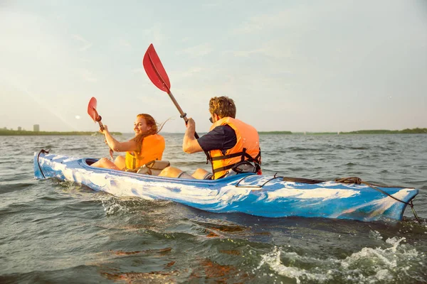 Pareja feliz kayak en el río con puesta de sol en el fondo —  Fotos de Stock