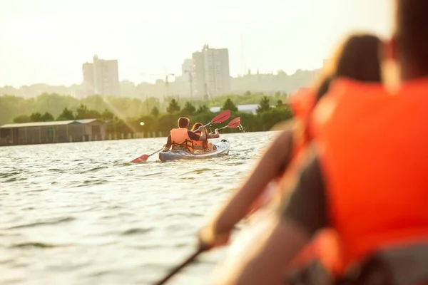 Pareja feliz kayak en el río con puesta de sol en el fondo —  Fotos de Stock
