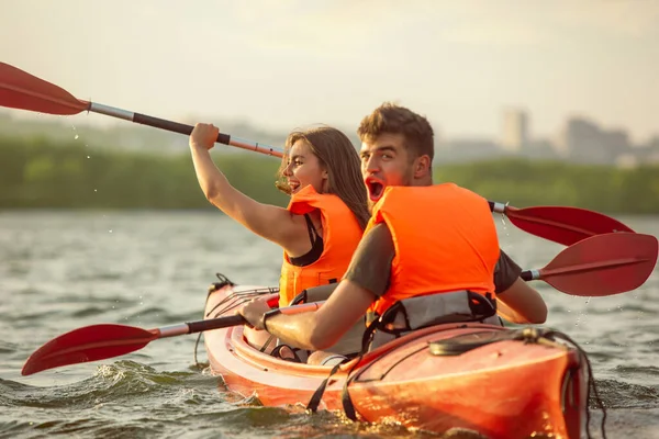 一对快乐的夫妇在河里划船，背景是日落 — 图库照片