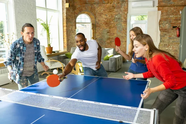 Jóvenes jugando al tenis de mesa en el lugar de trabajo, divirtiéndose —  Fotos de Stock