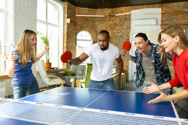 Jóvenes jugando al tenis de mesa en el lugar de trabajo, divirtiéndose —  Fotos de Stock