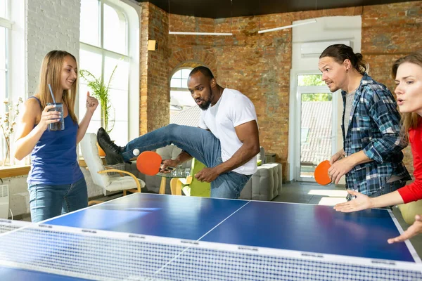 Jóvenes jugando al tenis de mesa en el lugar de trabajo, divirtiéndose —  Fotos de Stock