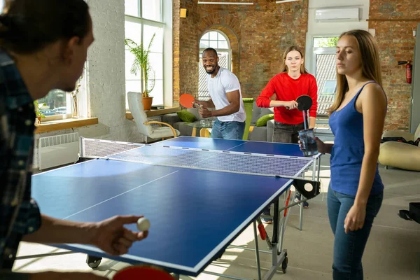 Jóvenes jugando al tenis de mesa en el lugar de trabajo, divirtiéndose —  Fotos de Stock