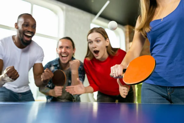 Jóvenes jugando al tenis de mesa en el lugar de trabajo, divirtiéndose —  Fotos de Stock