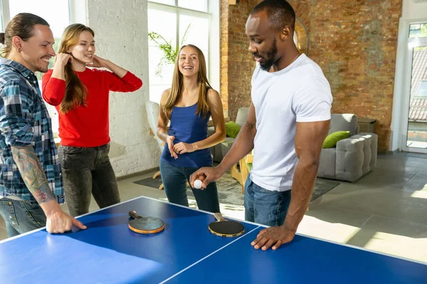 Jóvenes jugando al tenis de mesa en el lugar de trabajo, divirtiéndose —  Fotos de Stock