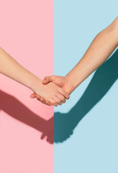 Руки женщины и мужчины держатся на розовом и голубом фоне — стоковое фото