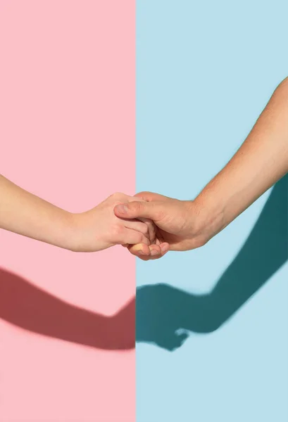 Руки женщины и мужчины держатся на розовом и голубом фоне — стоковое фото