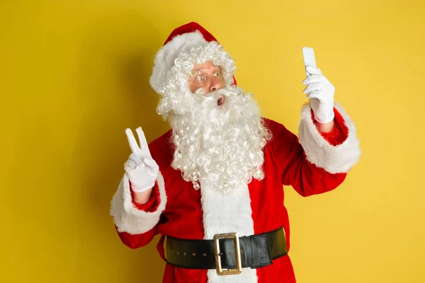 Babbo Natale con gadget moderni isolati su sfondo giallo studio — Foto Stock