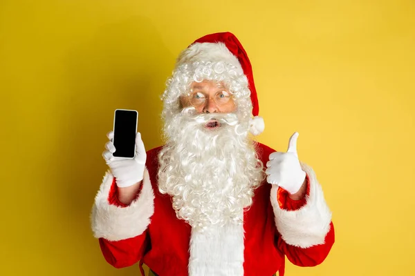 Kerstman met moderne gadgets geïsoleerd op gele studio achtergrond — Stockfoto