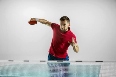 Genç adam beyaz stüdyo arka planında masa tenisi oynuyor.