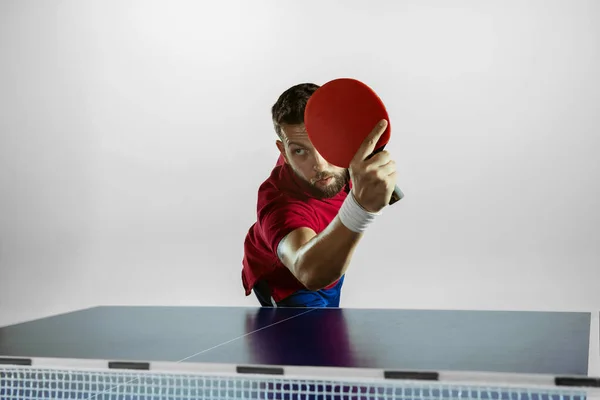 Jovem jogando tênis de mesa no fundo do estúdio branco — Fotografia de Stock