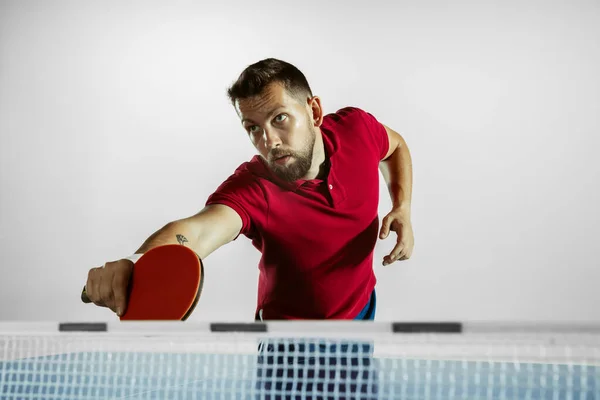 Jovem jogando tênis de mesa no fundo do estúdio branco — Fotografia de Stock