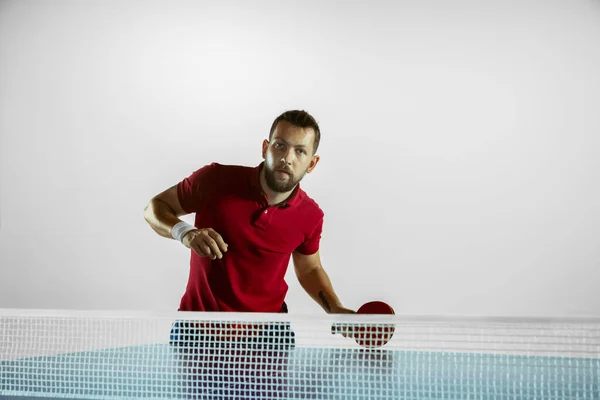 Joven jugando al tenis de mesa sobre fondo blanco del estudio — Foto de Stock