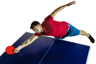 Genç adam beyaz stüdyo arka planında masa tenisi oynuyor.