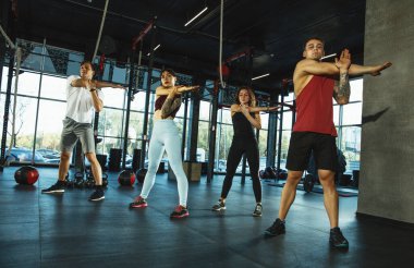 Spor salonunda spor yapan bir grup kaslı sporcu.