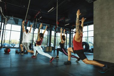Spor salonunda spor yapan bir grup kaslı sporcu.