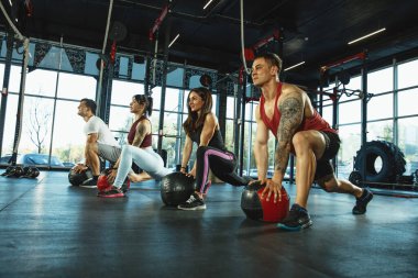 Spor salonunda spor yapan bir grup kaslı sporcu.