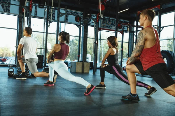 Spor salonunda spor yapan bir grup kaslı sporcu.