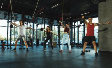 Spor salonunda spor yapan bir grup kaslı sporcu.