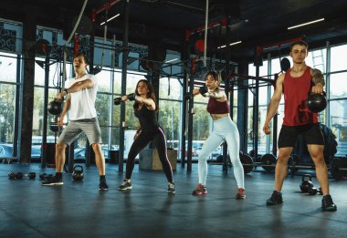 Spor salonunda spor yapan bir grup kaslı sporcu.
