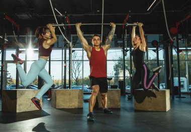 Spor salonunda spor yapan bir grup kaslı sporcu.