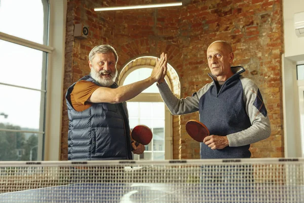 Uomini anziani che giocano a ping pong sul posto di lavoro, divertirsi — Foto Stock