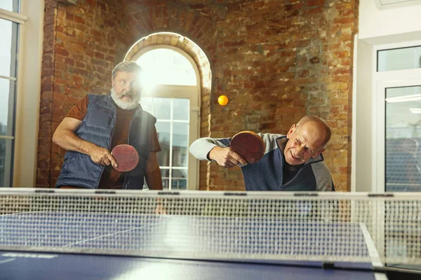 Uomini anziani che giocano a ping pong sul posto di lavoro, divertirsi — Foto Stock