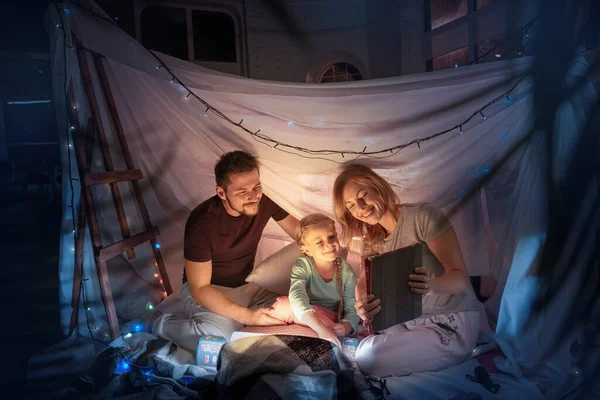 Familia sentada en un tipi, divirtiéndose con la linterna —  Fotos de Stock