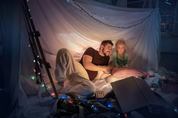 Vater und Tochter sitzen im Tipi und amüsieren sich mit der Taschenlampe — Stockfoto