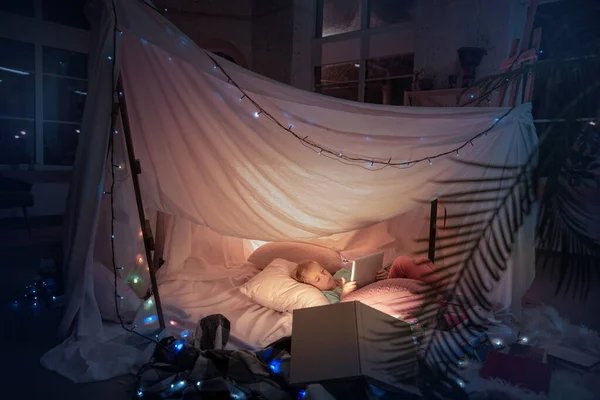 Menina deitada em uma tenda, brincando com a lanterna — Fotografia de Stock