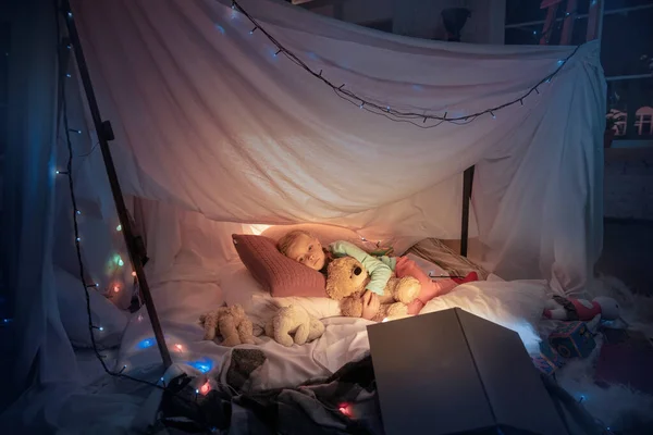Küçük kız çadırda uzanıyor, fenerle uyuyor. — Stok fotoğraf