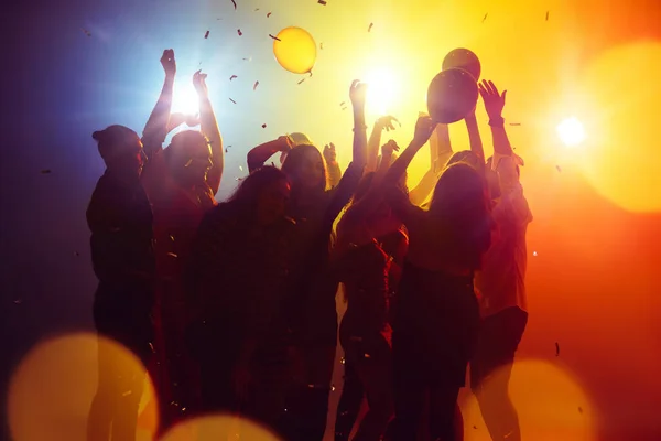 ฝูงชนในภาพเงา ยกมือขึ้นต่อต้านแสงนีออนสีสันบนพื้นหลังงานปาร์ตี้ — ภาพถ่ายสต็อก