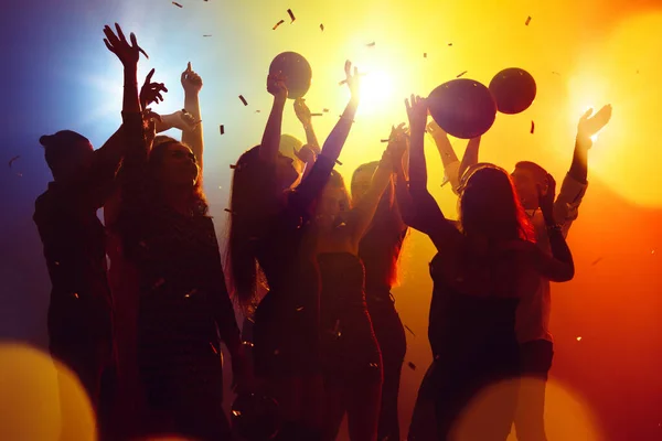 Silüetli bir kalabalık parti arka planındaki renkli neon ışığa karşı ellerini kaldırıyor. — Stok fotoğraf