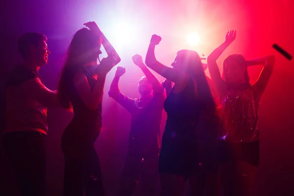 실루엣 을 하고 있는 군중은 파티 배경에 화려 한 네온 불빛을 향해 손을 들고 있다 — 스톡 사진