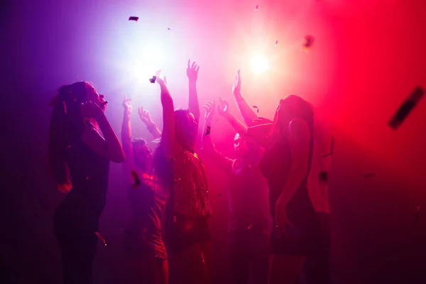 穿着人物造型的一群人在聚会背景下对着五颜六色的霓虹灯举手致意 — 图库照片