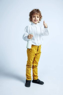 Beyaz stüdyo geçmişinde sıradan kıyafetler giyen hoş bir genç çocuk.