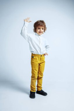 Beyaz stüdyo geçmişinde sıradan kıyafetler giyen hoş bir genç çocuk.