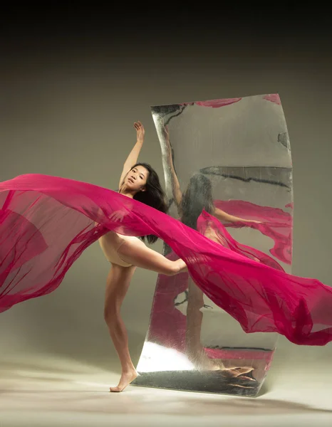 Young and stylish modern ballet dancer on brown background