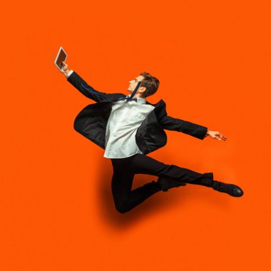 Günlük ofis tarzı giyinmiş bir adam stüdyo arka planında tek başına zıplıyor.