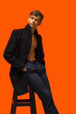 Turuncu arka planda yakışıklı bir gencin portresi.