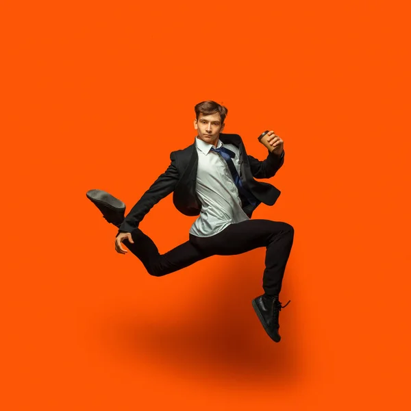 Мужчина в повседневной офисной одежде, прыгающий на фоне студии — стоковое фото