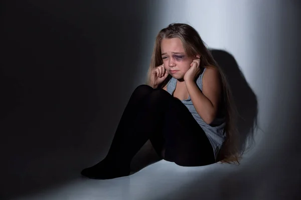 Trauriges und verängstigtes kleines Mädchen mit Blutanfall und blauen Augen, das verängstigt sitzt — Stockfoto