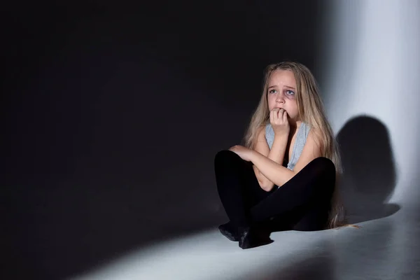 Triste e assustada menina com sangue e olhos machucados sentado com medo — Fotografia de Stock