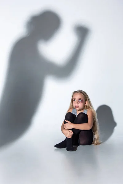 Trauriges und verängstigtes kleines Mädchen mit Blutanfall und blauen Augen, das verängstigt sitzt — Stockfoto