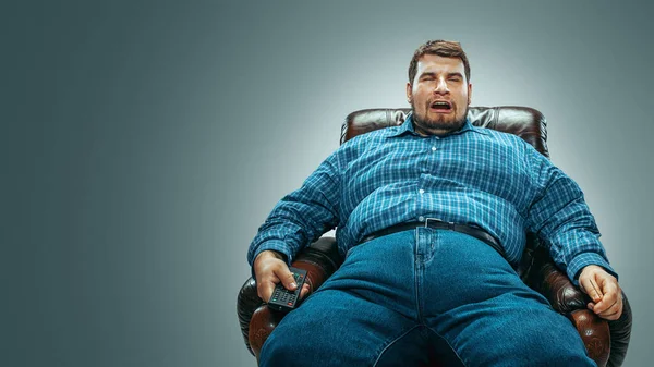 Gros homme assis dans un fauteuil brun, émotionnel regarder la télévision — Photo