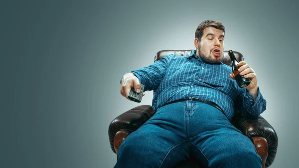 Gordo sentado em uma poltrona marrom, emocional assistindo TV — Fotografia de Stock