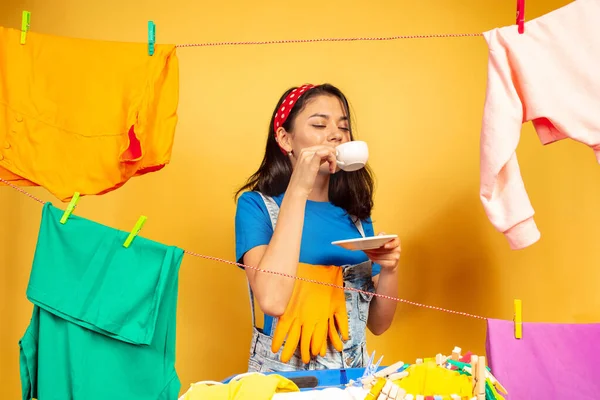 Divertida y hermosa ama de casa haciendo tareas domésticas sobre fondo amarillo — Foto de Stock