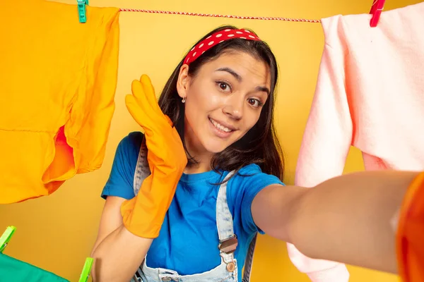 Engraçado e bela dona de casa fazendo tarefas domésticas no fundo amarelo — Fotografia de Stock